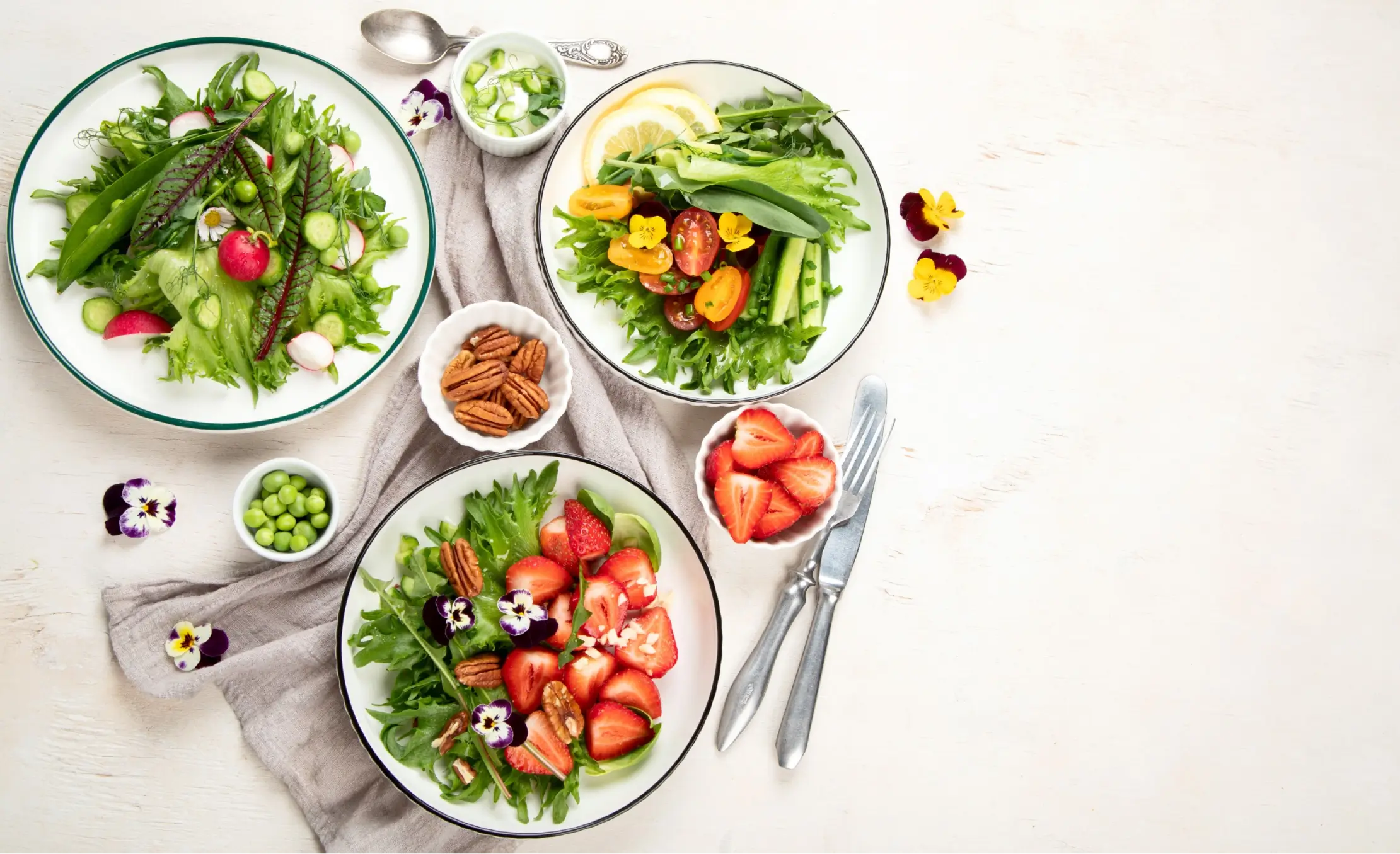 there are four plates of food on a table with forks and spoons