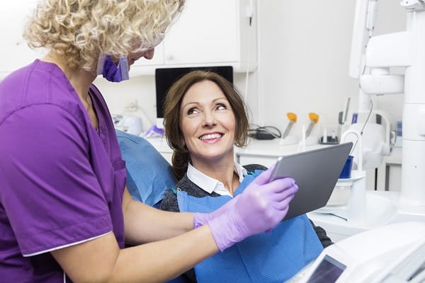 woman in purple shirt and purple gloves sitting in dental chair