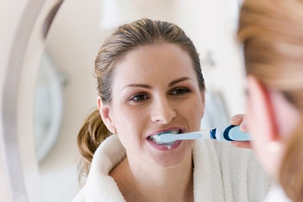 Woman looking at mirror and brushing teeth