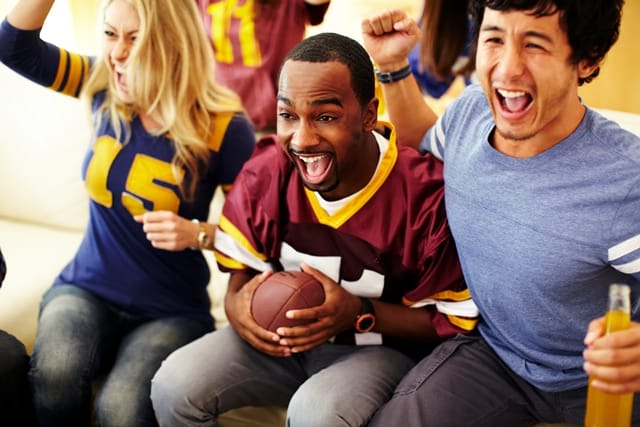 several people sitting on a couch watching a football game