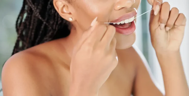 woman brushing her teeth with a toothbrush in front of a window
