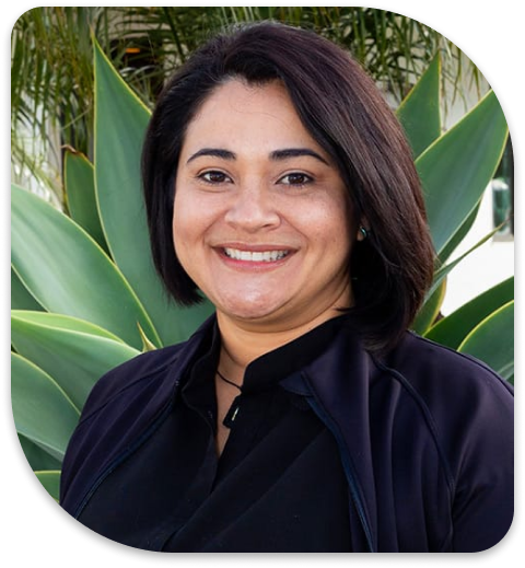 smiling woman in black shirt with large green plant in background