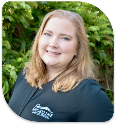 a close up of a woman with a black shirt and a green bush behind her