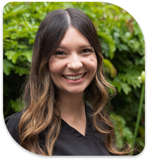 smiling woman with long hair and black shirt in front of bushes