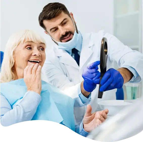 Senior woman sitting in a dental chair with a male dentist holding a mirror, highlighting adult dentistry care.