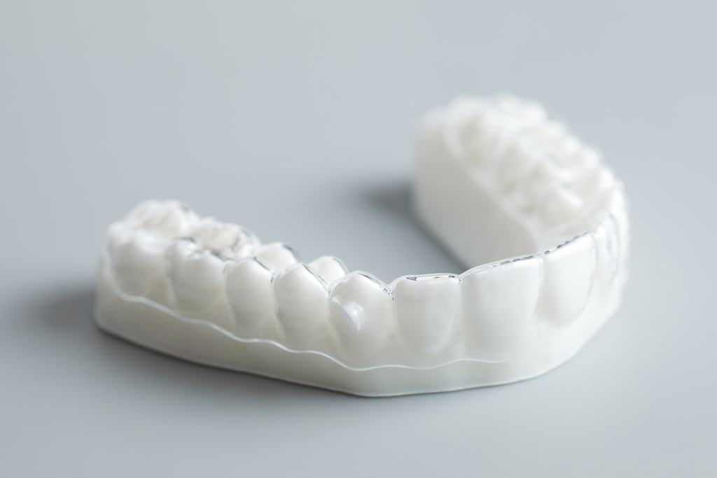 Clear Invisalign aligner tray displayed on a dental model with white teeth.